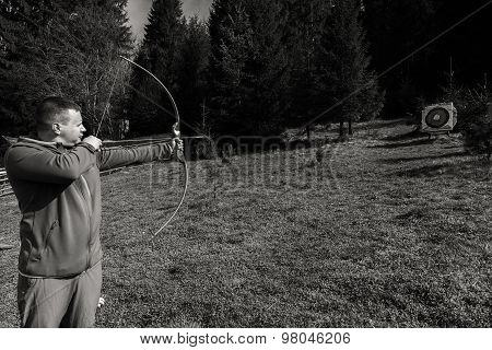 A man shoots a bow. Man engaged in archery.