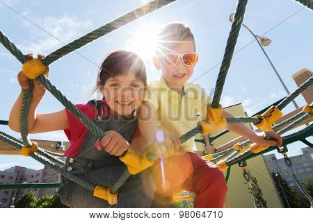 summer, childhood, leisure, friendship and people concept - group of happy kids on children playground climbing frame