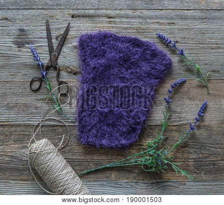 Rich violet clothing for baby girl, selfmade, lying on a dark table with flowers, topview