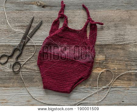 Adorable dark red laced switsuit for a baby girl, handmade, on dark table, topshot
