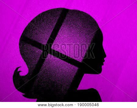 Silhouette of long-haired woman on a pink background. On the hair is a glass texture with black strips. An unusual profile of a beautiful girl. Double exposure.