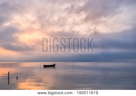 Old rowboat on the lake at sunset
