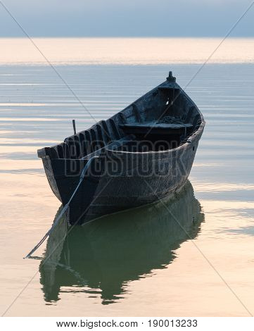 Old rowboat on the lake at sunset