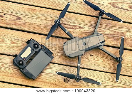 Drone quadcopter with a flight controller over wooden background. Top view flat lay