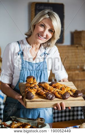 Female staff holding sweet foods in bakery section of supermarket