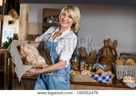 Female staff holding basket of sweet foods in bakery section of supermarket