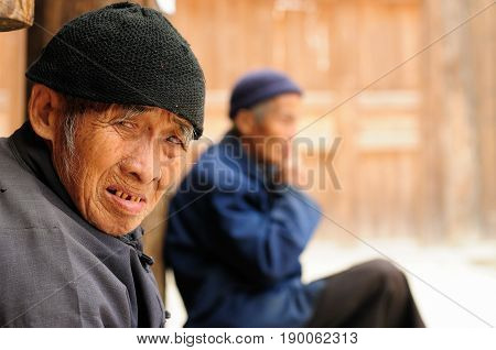 ZHAOXING CHINA - 11 NOVEMBER 2010: Old Chinese resting on the doorstep of his cottage in the village Zhaoxing
