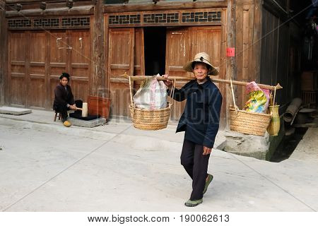 ZHAOXING CHINA - 12 NOVEMBER 2010: Residents of the Zhaoxing is a pretty Dong minority town carrying things on the stick for the sale