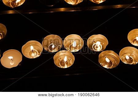 Rows of burning candles in a dim church