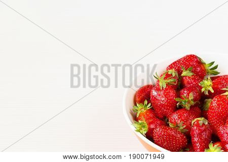 Red fresh strawberries in a bowl isolated on white background. Close up view.