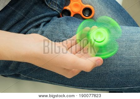 trendy fidget spinner - person holding spinning green fidget spinner in hand, close up view