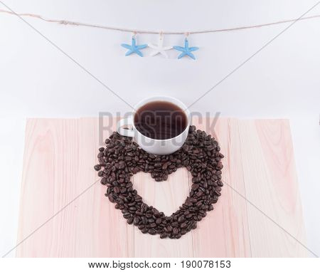 Heart of coffee beans and white cup and black coffee with white background.
