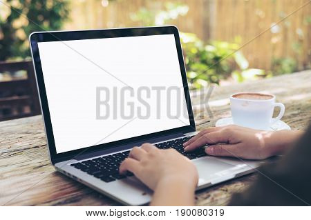 Mockup image of hands using and typing on laptop with blank white screen on vintage wooden table in outdoor cafe