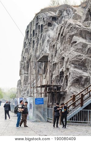 Visitors Near Carved Rocks In Longmen Grottoes