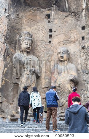 Tourists Near Buddhist Sculptures In Grotto