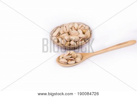 Delicious  pistachio in wooden spoon and the basket on white background