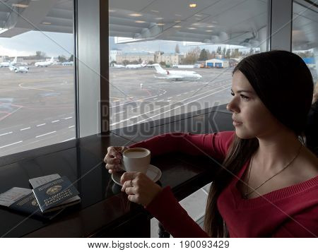 Girl in airport's business lounge with cup of coffee.