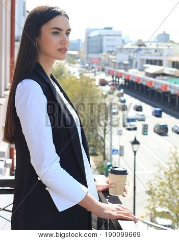 Closeup portrait of relaxing on balcony business woman isolated on background of city buildings
