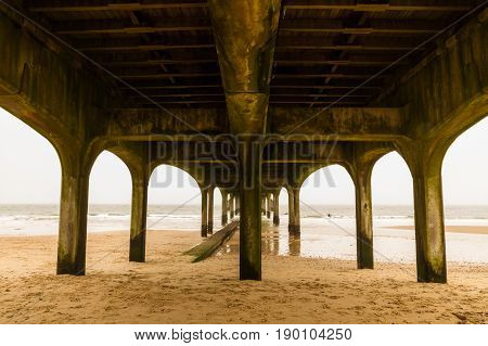 View to sea below concrete pier on sandy beach. Boscombe Pier Bournemouth Dorset England United Kingdom.