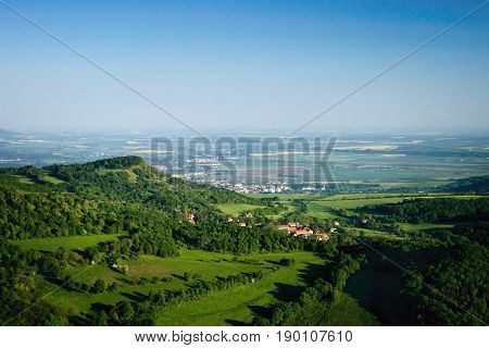 Ceske Stredohori tourist area with hill Kamyk and Litomerice city on horizont and Kundratice village in foreground in spring evening czech landscape during sunset