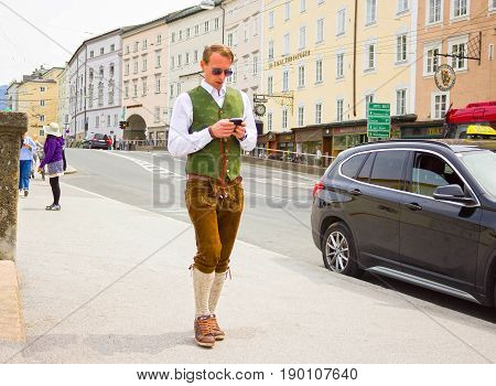 Salzburg, Austria - May 01, 2017: Men wearing traditional Austrian costume going with mobile phone at street on sunny day at Salzburg, Austria on May 01, 2017