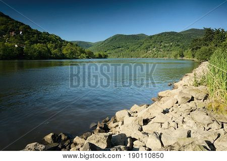 Valley of european river Labe with stones on foreground in spring afternoon in czech landscape