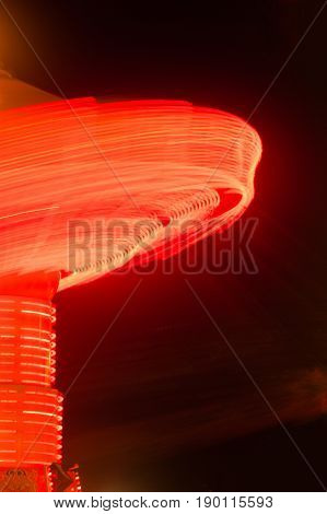 Lights going around on a carnival ride create red streaks
