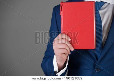 red book in hand of man or businessman in blue outfit on grey background copy space business saving book
