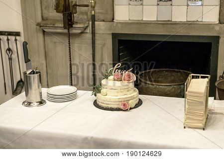 Beautiful wedding cake with cream With text Love on top and pink flowers roses
