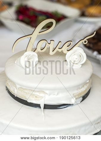 Beautiful wedding cake with cream With text Love on top and pink flowers roses