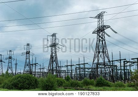 Transformer substation and high voltage tower on a background of clouds.