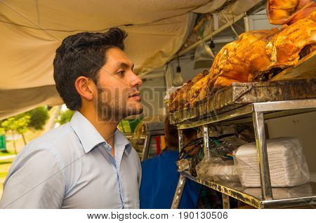 Handsome young man watching a delicious hornado roasted pork, ecuadorian traditional typical andean food.