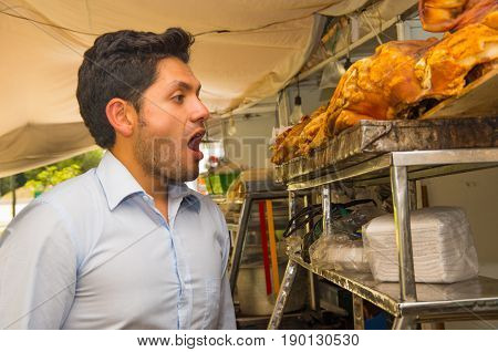 Handsome young man got shocked watching a delicious hornado roasted pork, ecuadorian traditional typical andean food.