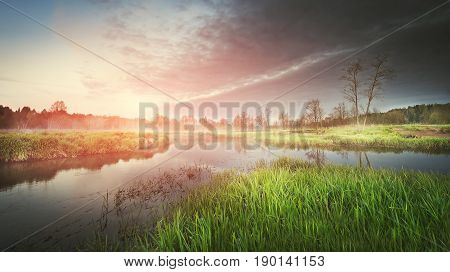 A landscape of nature on a summer morning on the river at sunrise. The colorful sky and reflections in the river are filled with freedom and tranquility.