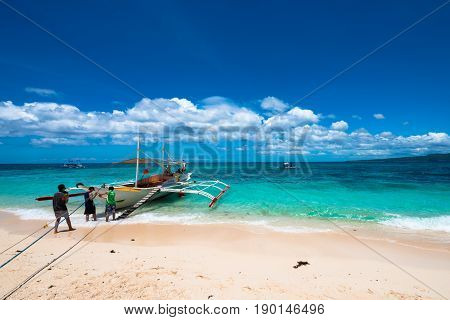 BORACAY, WESTERN VISAYAS, PHILIPPINES - MARCH 25, 2017:  Boat at Puka Beach at the northern end of Barocay Island in the Visayas region of Philippines. Local men brings lots of tourists everyday.