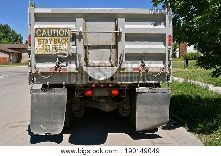 A construction parked truck parked in a residential street posts a warning sign on the rear of the box, 