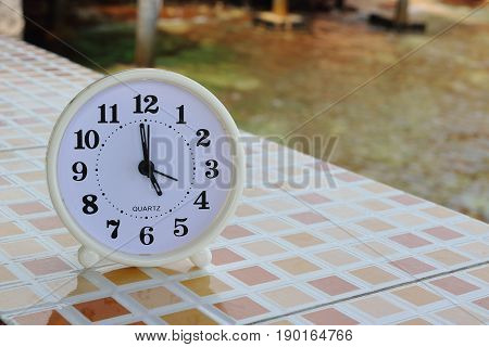 White clock at 5pm on the tiled floor and seashore background Freedom concept