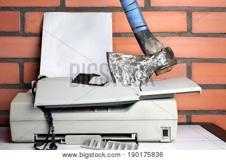 A blank paper sheet in a printer smashed with axe concept of aggression and bureaucracy