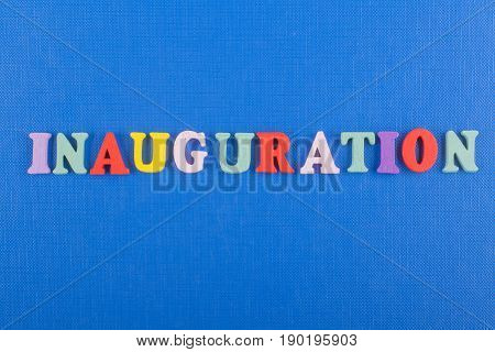 Iinauguration . English word on blue background composed from colorful abc alphabet block wooden letters, copy space for ad text. Learning english concept
