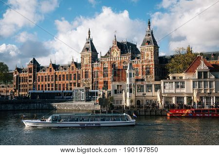 Amsterdam Netherlands - 25 April 2017: Cityscape of central railway station and old town canal with tourist vessels Amsterdam Holland