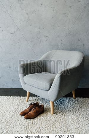 Brown Leather Oxford Shoes On Carpet Near Textile Armchair At Empty Room