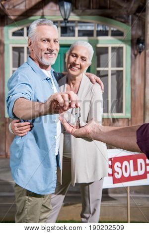 Saleman Giving Keys Of New House To Happy Senior Couple