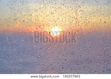 Drops of water on the glass. Sunrise behind the window