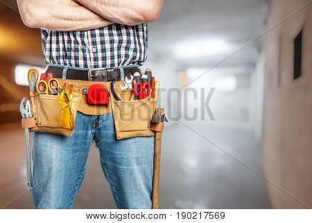 handyman with toolsbelt and crossed arms blurred background