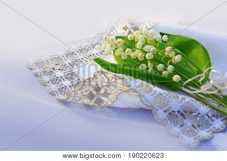 Lily of the valley bouquet on the table with the cloth napkins.