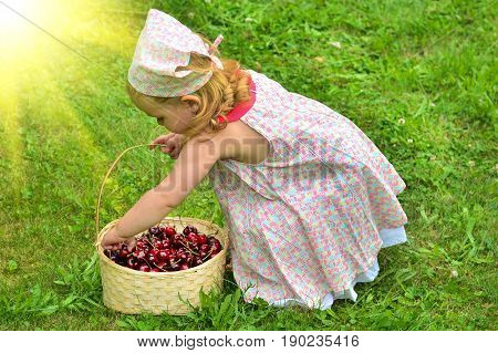 Girl in a dress with a basket of cherries
