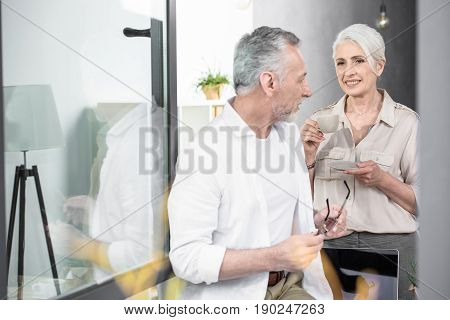 Senior Colleagues Converse Near Opened Vindow At Office