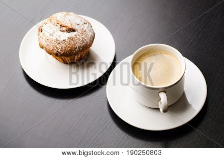 cup of coffee and muffin on black table, view frim above