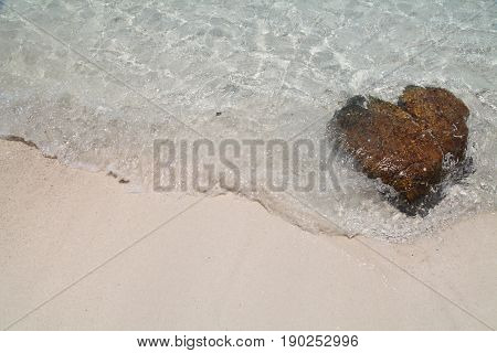 heart shaped stone and beautiful wave on white sand beach at thailand