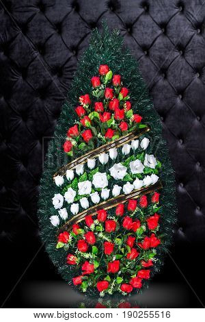 Luxury Funeral wreath with red and white flowers isolated on royal dark background. Ritual object for funeral